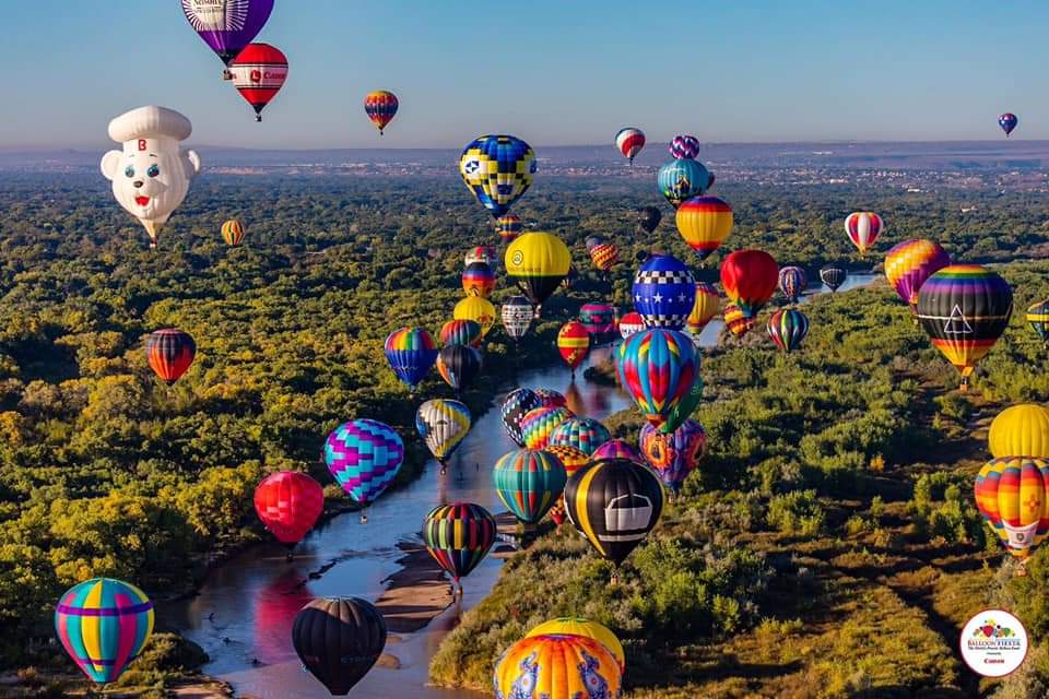 hot air balloons flying over the Rio Grande River during Albuquerque International Balloon Fiesta - TravelsWithSuz.com