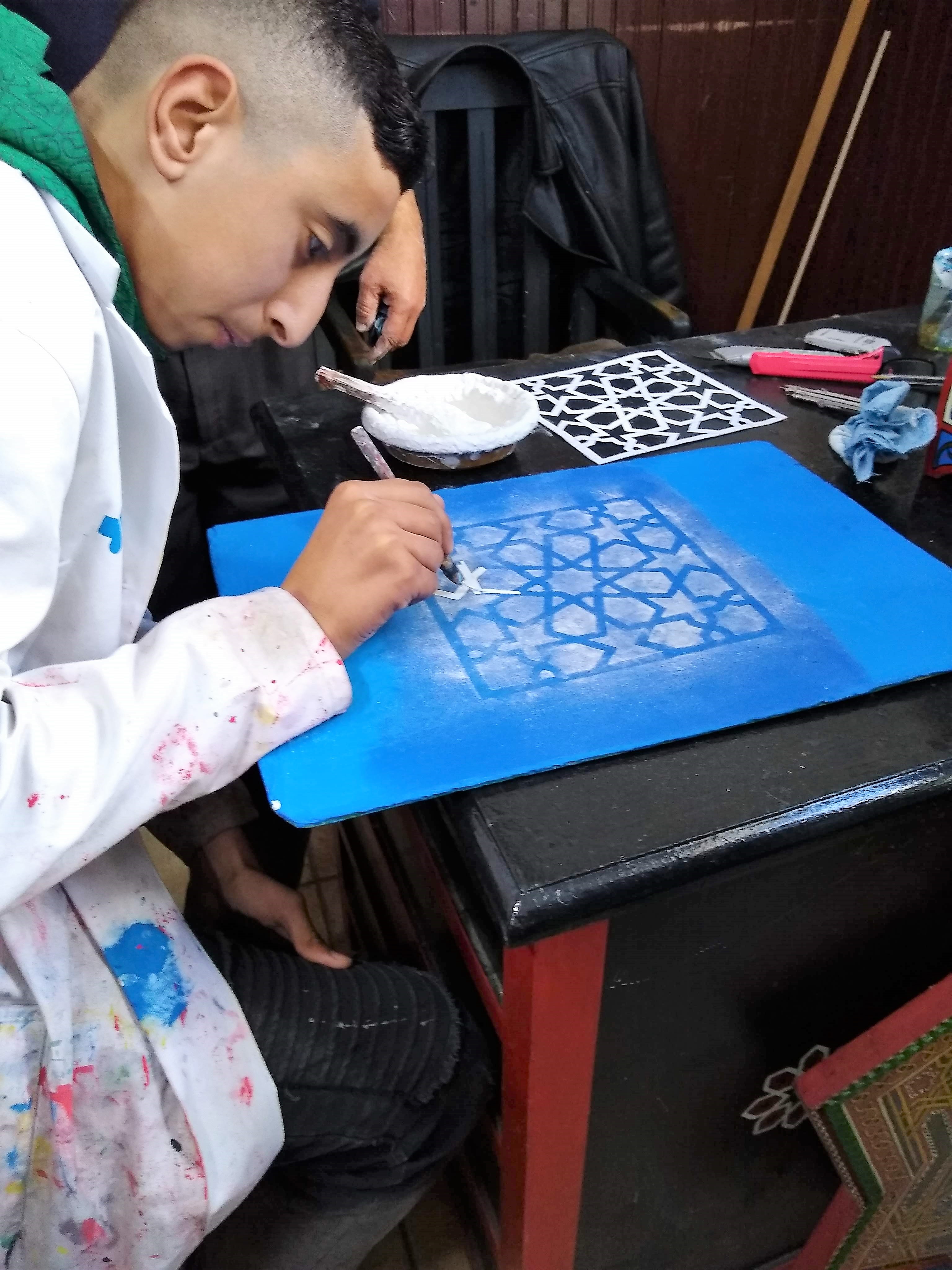 student points stencil at Dar Sanaa, a traditional craft school in Tetouan
